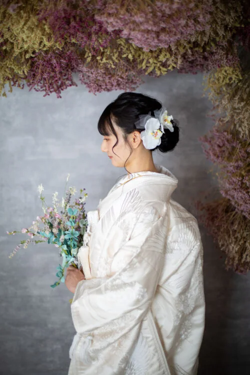 花を背景に白無垢をまとった花嫁の横顔